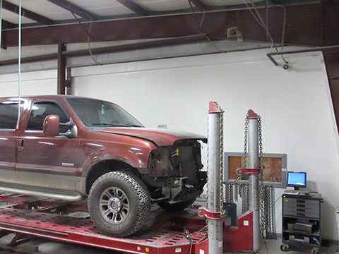Red truck on a lift inside the auto repair shop | Auto Repair in Cartersville, GA by Candy Apple Custom Collision II