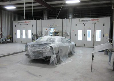 Car covered in plastic inside repair shop | Red truck on a lift inside the auto repair shop | Collision Repair in Cartersville, GA by Candy Apple Custom Collision II