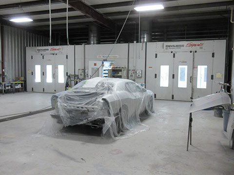 Car covered in plastic inside repair shop | Red truck on a lift inside the auto repair shop | Collision Repair in Cartersville, GA by Candy Apple Custom Collision II